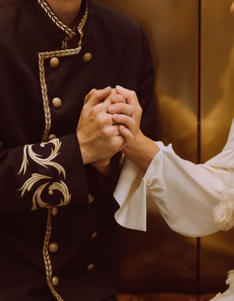 A man in vintage hotel uniform holding hands with a woman, creating a moment of connection.